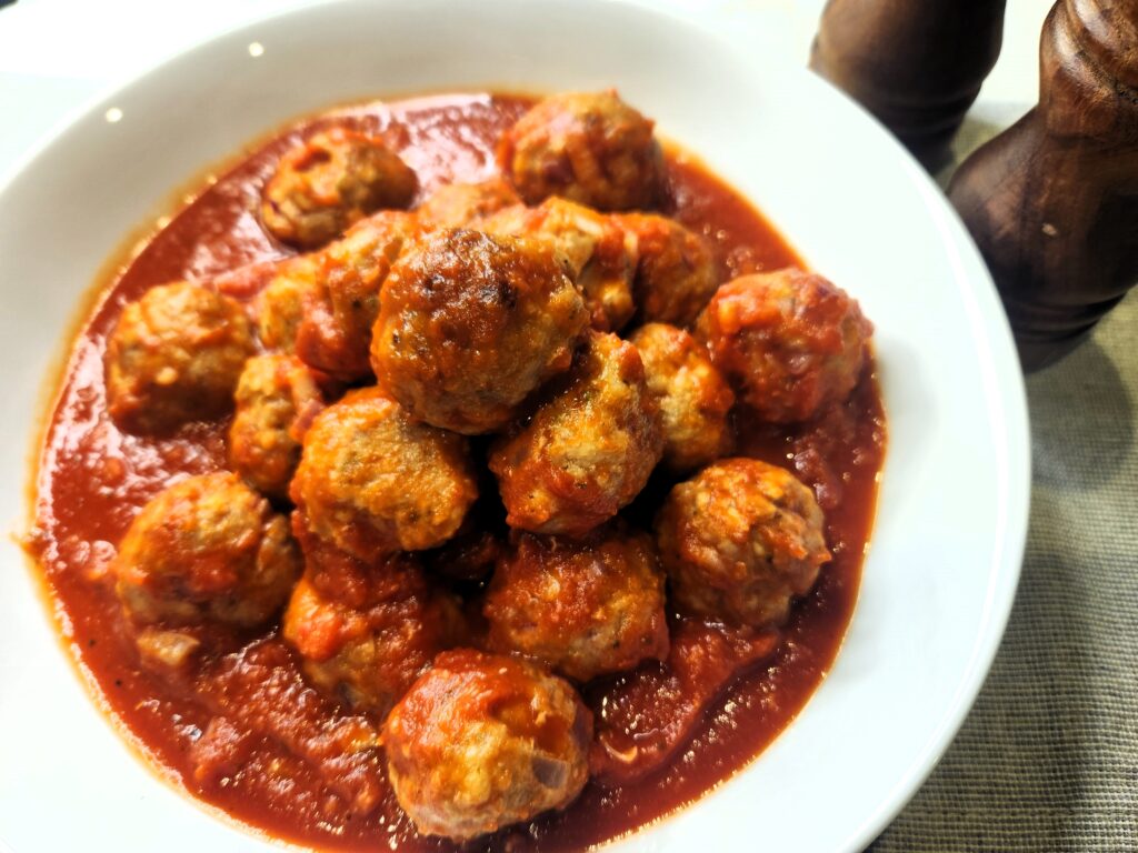 Perfect Turkey Meatballs showcased in a snow white bowl. Featuring our favorite wooden salt and pepper grinders.
