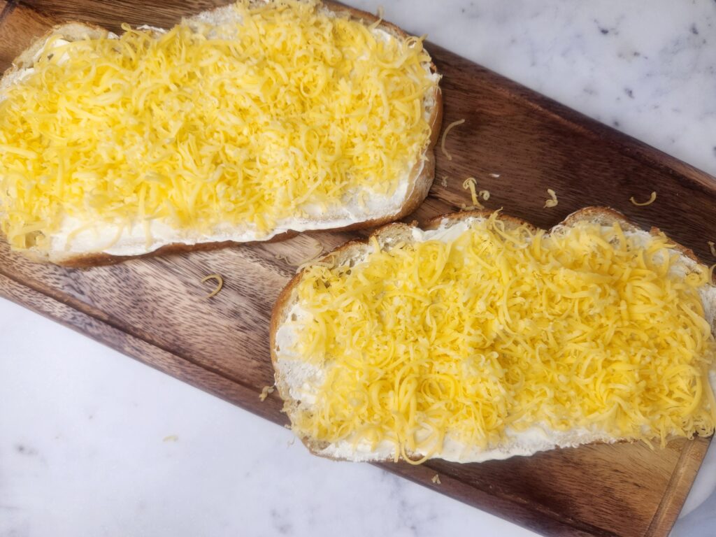 Spread cheese on buttered side of bread for Sinful Grilled Cheese