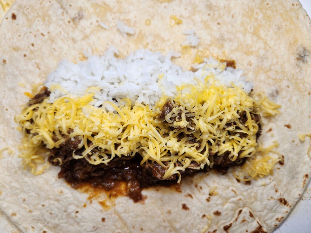 Assemble burrito with chunky beef, rice, and cheese, Smothered Chunky Beef Burritos